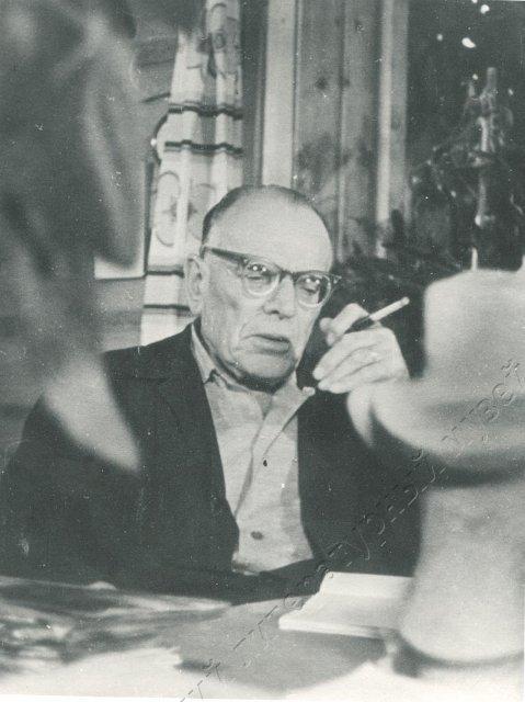 Фотография ч/б. Паустовский К. Г. сидит за столом своего кабинета, в левой руке сигарета. Таруса. Перепечатка Коршункова А. с негатива фильма "Дорога к Чёрному озеру" из архива Г. А.Арбузовой. 1966 г. 1966 г.